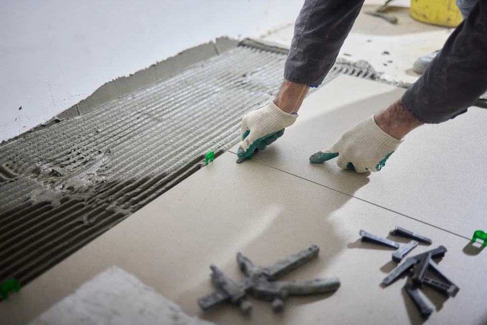 Ouvrier carreleur en chantier intérieur posant du carrelage au sol