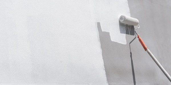 Un artisan applique de l'enduit de lissage sur un mur intérieur blanc à l'aide d'une spatule large