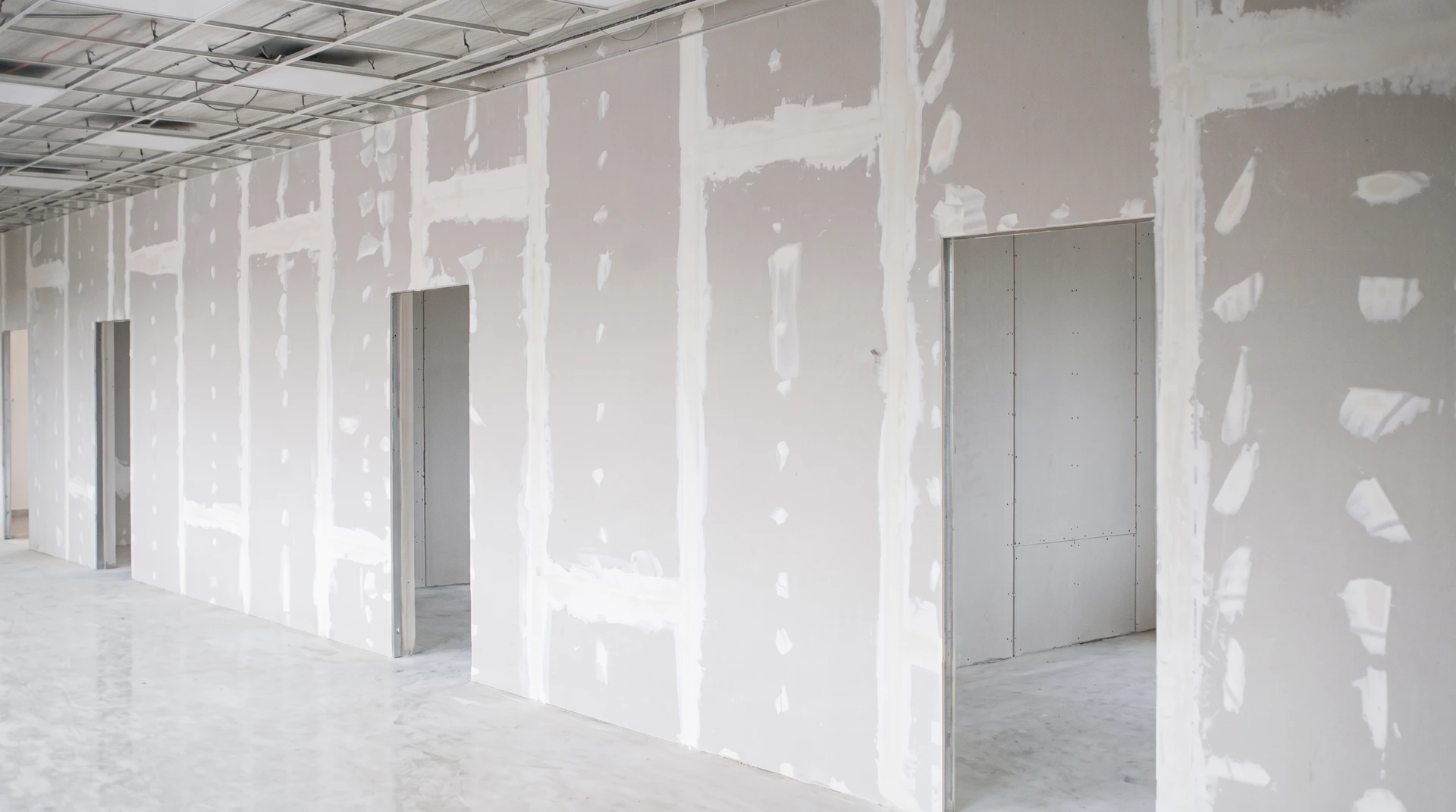 Ouvrier en bâtiment installant des plaques de plâtre sur ossature métallique