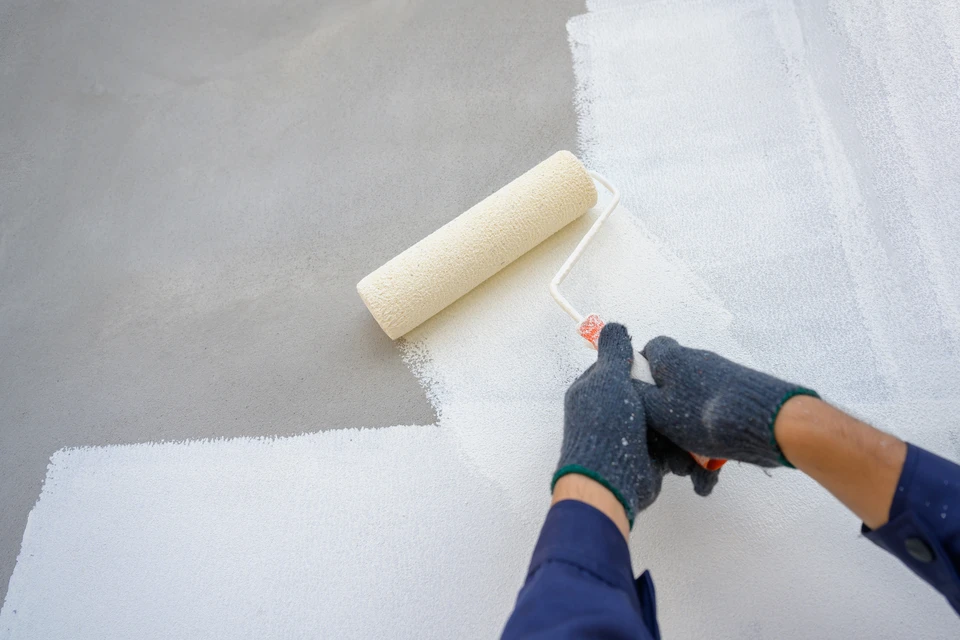 Christopher Gouverneur et sa fille travaillant ensemble sur un chantier de rénovation intérieure, préparant un mur pour la peinture. Ils sont face à la caméra, tous deux en tenue de chantier, concentrés et souriants, incarnant un duo d'artisans complémentaires et solidaires sur le terrain.